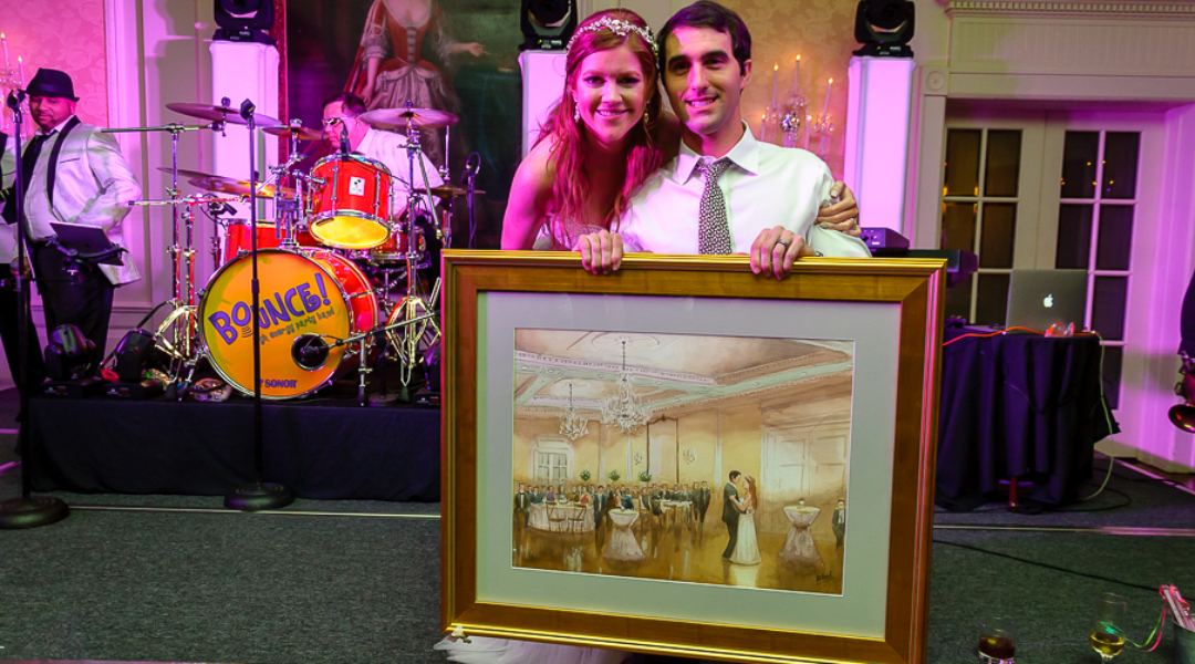 Bride and Groom at their wedding reception holding a beautiful painting of their first dance painted live by artist Tesh Parekh.